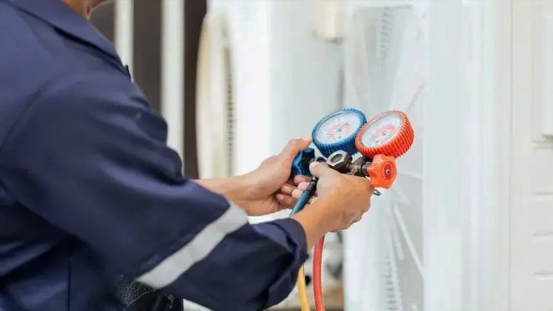 Technician diligently monitoring a digital micron gauge during AC evacuation