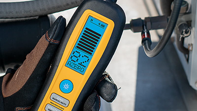 Technician checking for refrigerant leaks with a detector