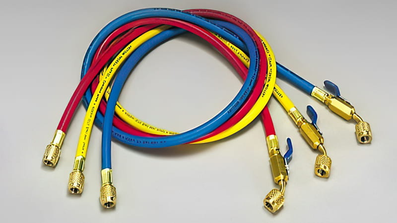 A technician holding up two different hoses for comparison: a thick, black, large-diameter vacuum hose in one hand, and a standard, thin yellow charging hose in the other