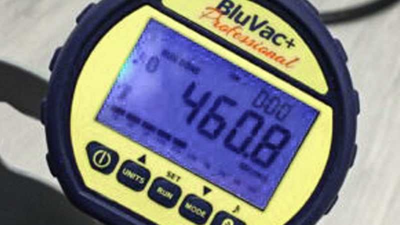 A close-up on a digital micron gauge showing a stable reading of 475 microns during a standing vacuum test