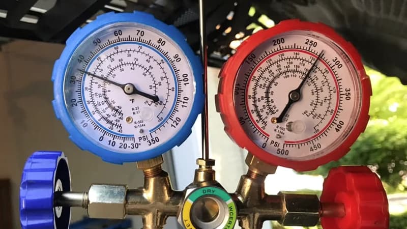 A close-up shot of a recovery machine's pressure gauge with the needle pushed far into the red danger zone