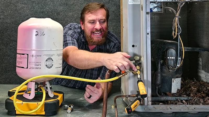 Refrigerant cylinder on a scale, with hoses connected to an HVAC manifold gauge set and the AC unit