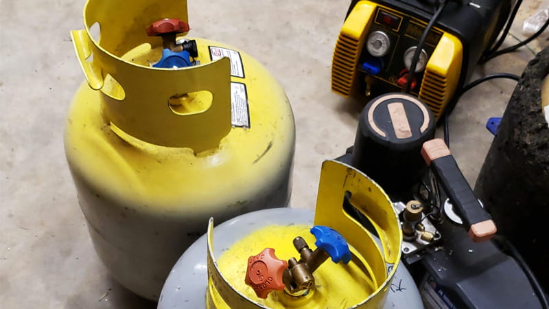 A safe setup showing two recovery tanks connected to each other via a manifold gauge set, demonstrating a tank-to-tank refrigerant transfer