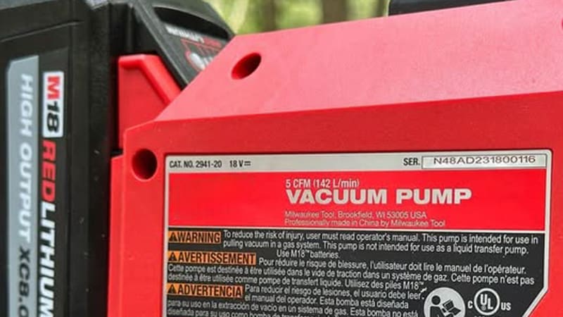 A side-by-side comparison shot of a compact, modern battery vacuum pump and a larger, traditional corded vacuum pump on a workbench